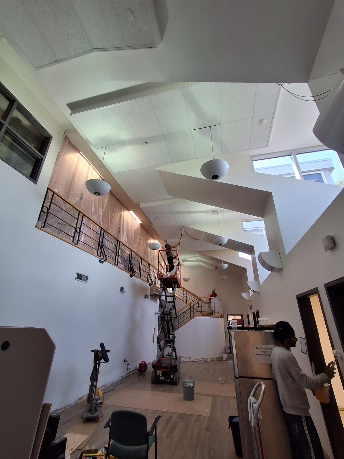 TrueCoat Painting crew painting a high mezzanine ceiling and wall on a commercial jobsite