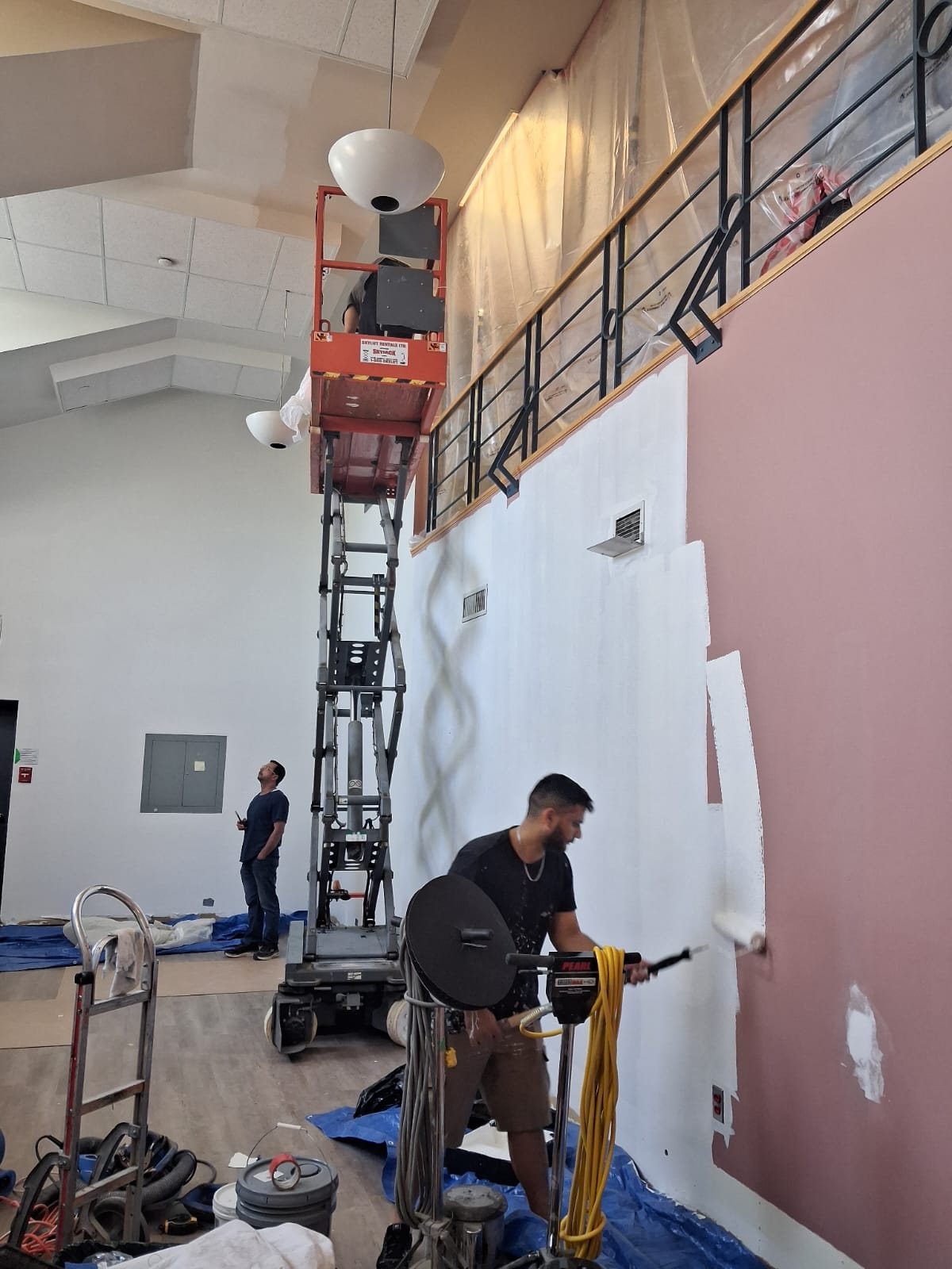 TrueCoat Painting crew on a scissor lift priming a wall for a commercial project in Brampton