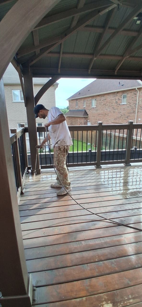 TrueCoat Painting crew spraying stain onto a covered deck floor in the GTA