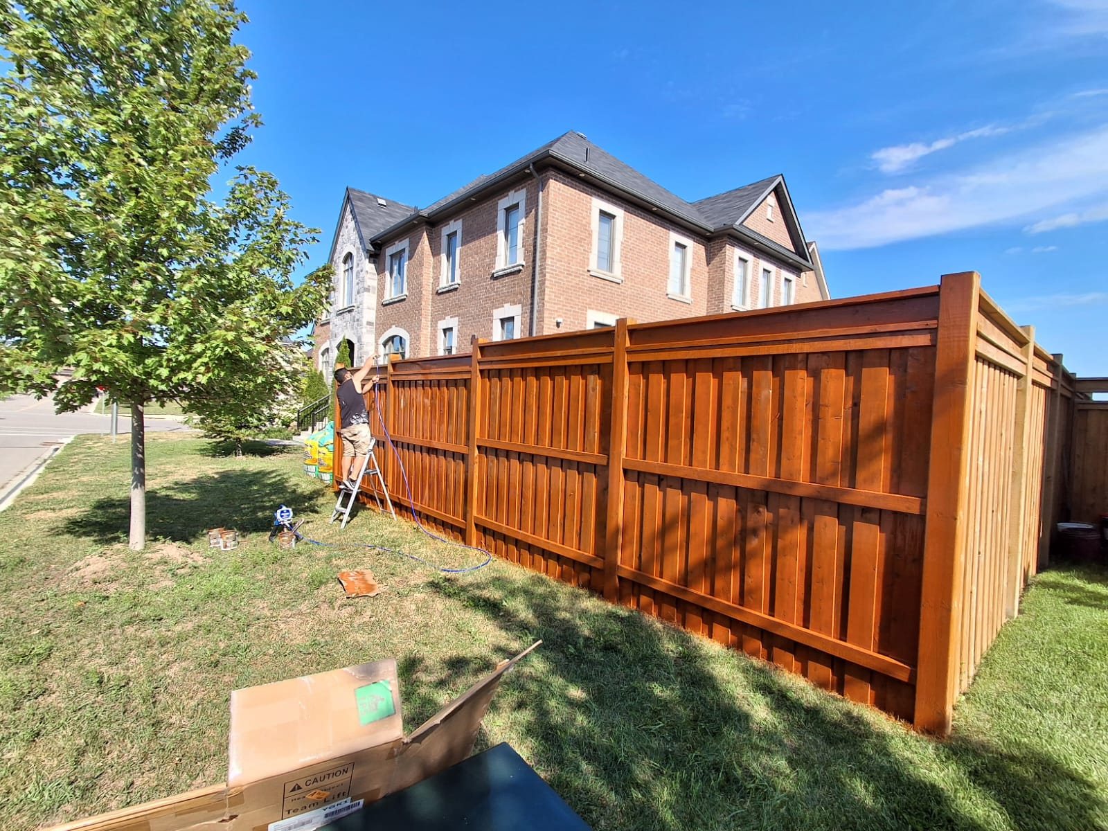 TrueCoat Painting crew staining a wood fence a rich amber tone in the GTA